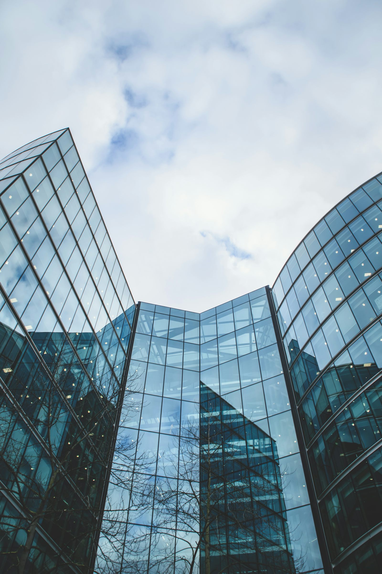 Glass curtain-wall building facade against a moody sky